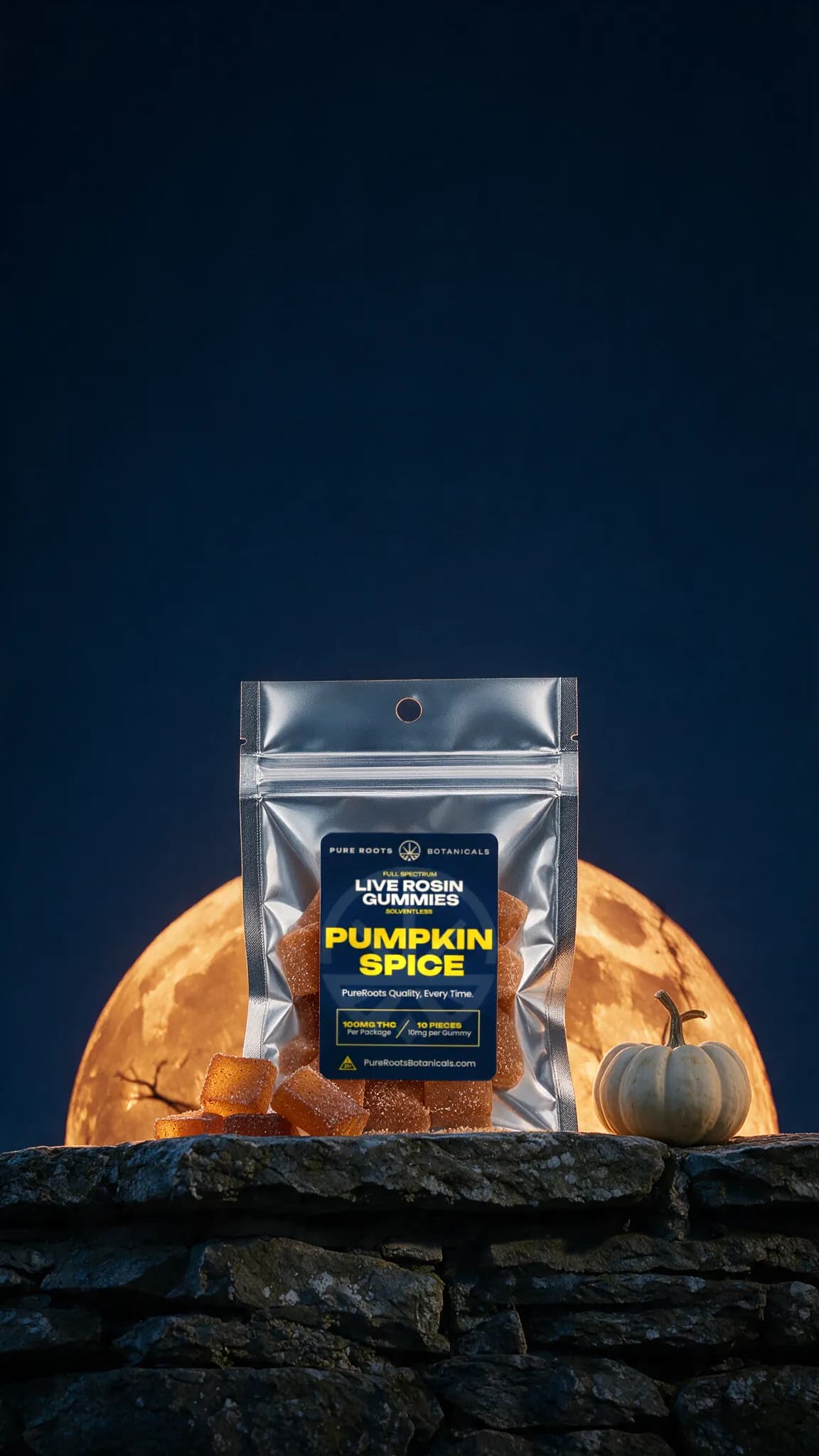 A silver Pure Roots Pumpkin Spice live rosin gummies pouch on a stone wall at night in front of a huge orange harvest moon, with sugar-coated gummies and a small white pumpkin