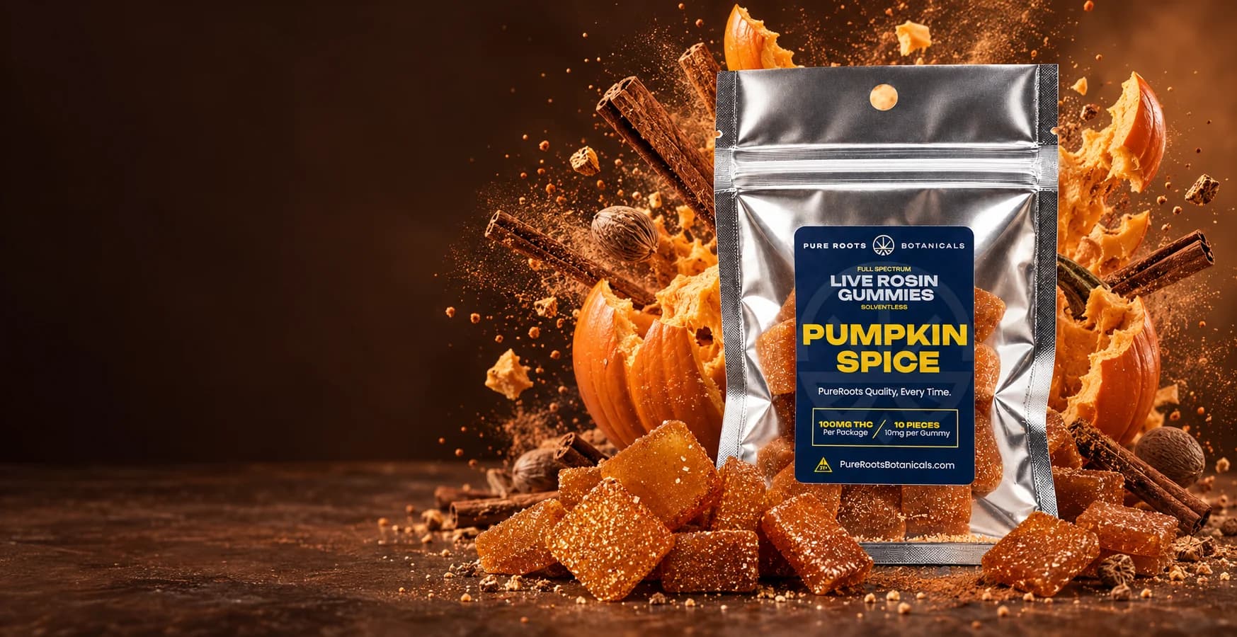 A silver Pure Roots Pumpkin Spice live rosin gummies pouch in front of a bursting pumpkin, cinnamon sticks and spice dust, with sugar-coated gummies in the foreground