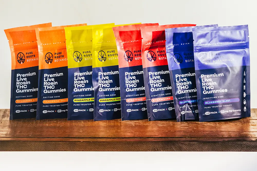 Assorted Pure Roots Botanicals Delta-9 THC gummies made with live rosin, featuring multiple strains including Tangerine Dream, Pineapple Paradise, Strawberry Frost, and Blueberry Blast